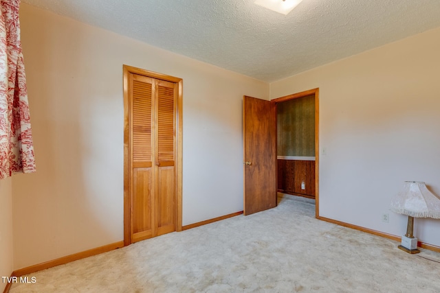 unfurnished bedroom featuring light carpet, a textured ceiling, and a closet