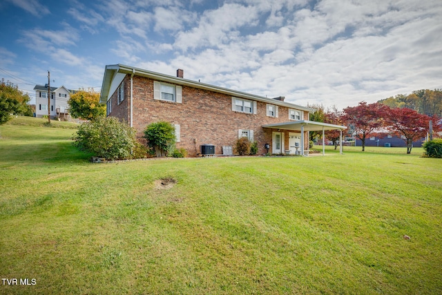 rear view of property with central AC and a lawn