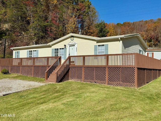 rear view of property featuring a wooden deck and a lawn