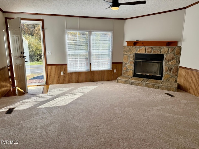 unfurnished living room with wooden walls, ceiling fan, a textured ceiling, and plenty of natural light