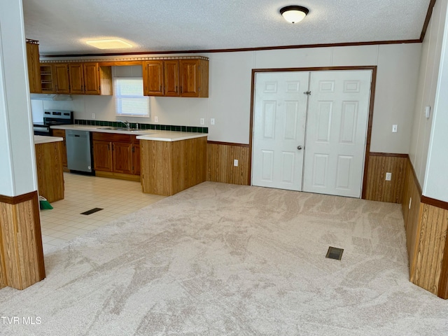 kitchen featuring kitchen peninsula, appliances with stainless steel finishes, a textured ceiling, sink, and light colored carpet