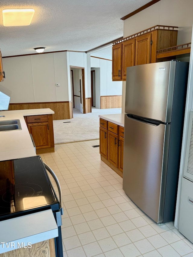 kitchen with stove, stainless steel fridge, a textured ceiling, and wood walls