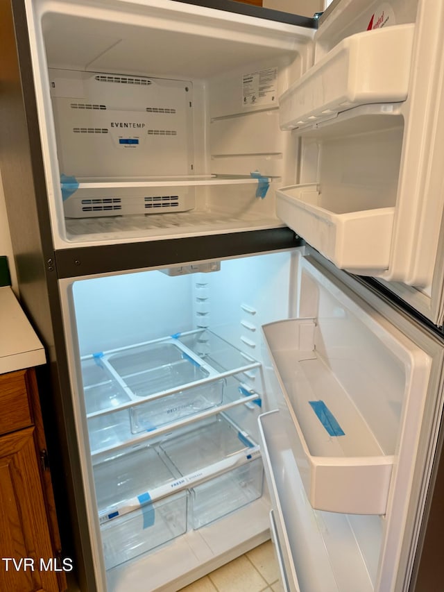 interior details featuring white fridge and light tile patterned floors