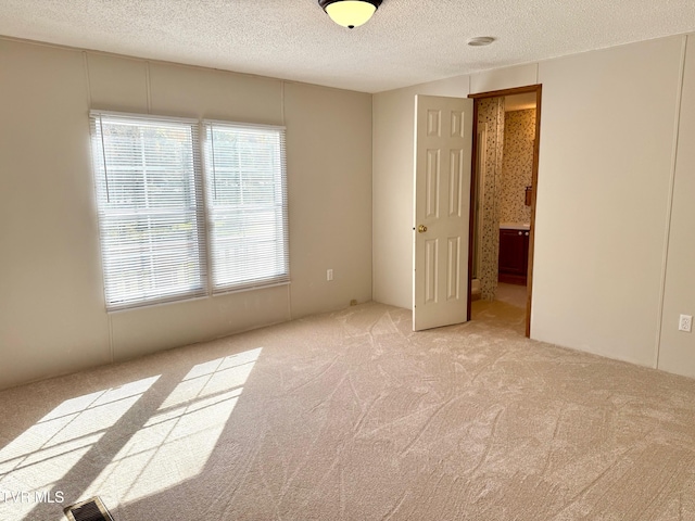 unfurnished bedroom with a textured ceiling and light colored carpet