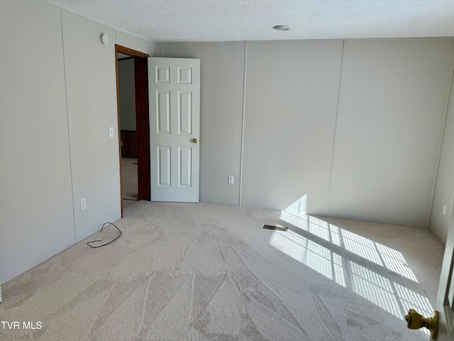 empty room featuring a textured ceiling and light colored carpet