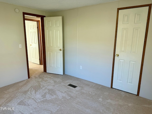 unfurnished bedroom with light carpet and a textured ceiling