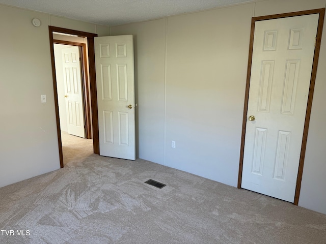 unfurnished bedroom featuring a textured ceiling and light colored carpet