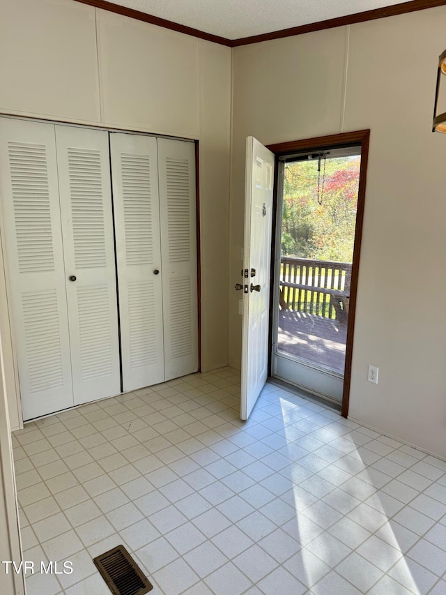 interior space with a closet, a textured ceiling, light tile patterned flooring, and access to exterior