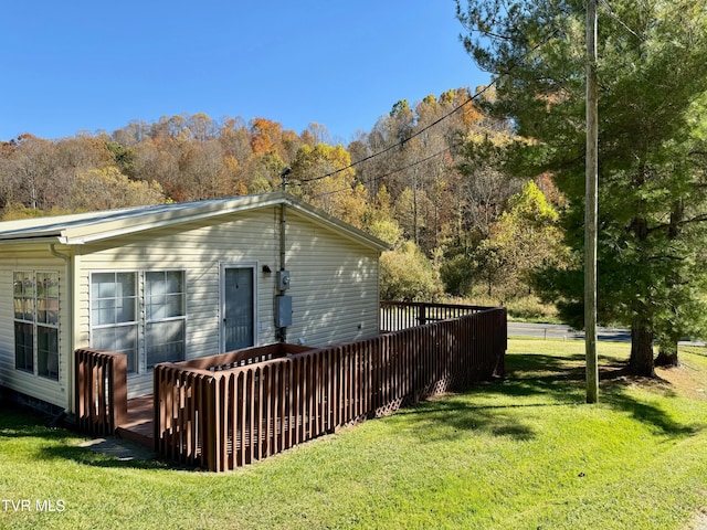 back of house with a deck and a lawn