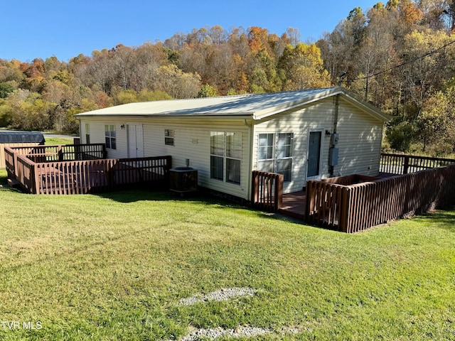 back of house with central air condition unit, a deck, and a lawn