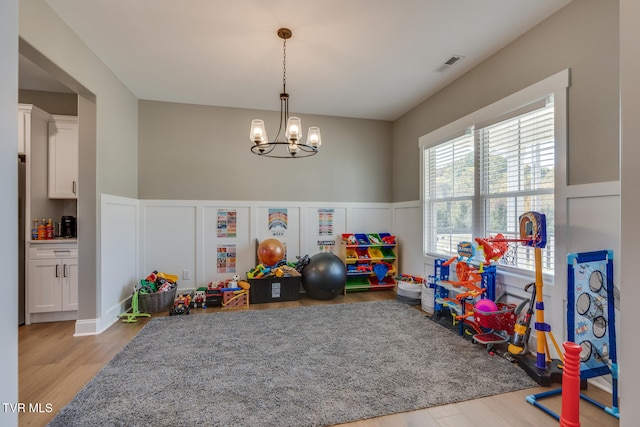 playroom featuring a chandelier and light wood-type flooring