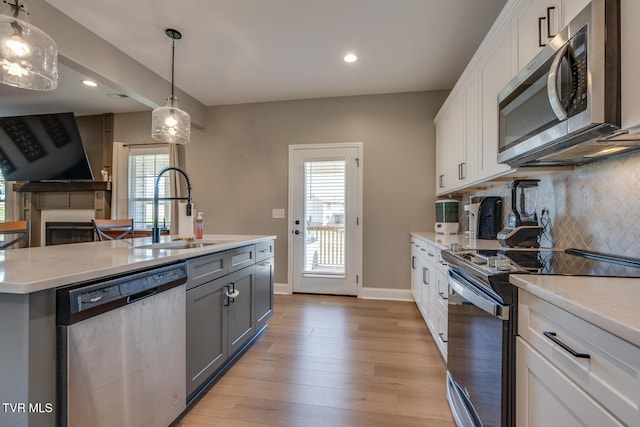 kitchen featuring appliances with stainless steel finishes, sink, a wealth of natural light, and white cabinets