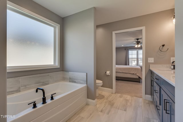 bathroom with a tub to relax in, vanity, toilet, and ceiling fan