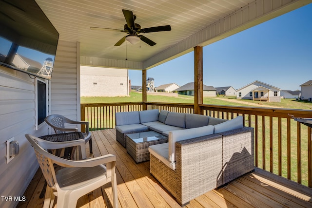 wooden deck with an outdoor living space, a lawn, and ceiling fan