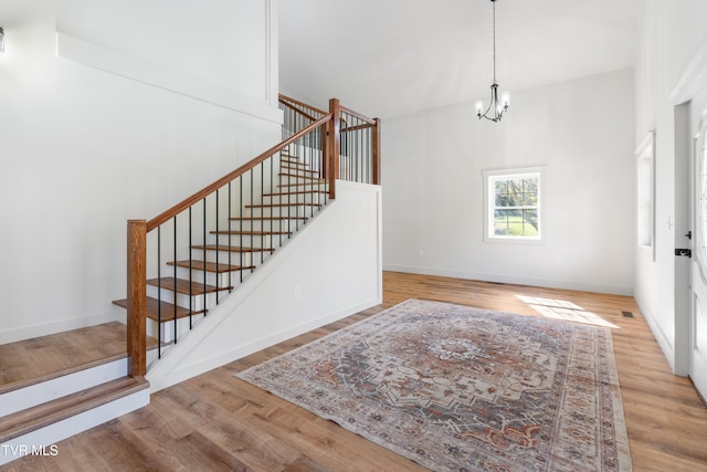 entryway featuring light hardwood / wood-style floors, a notable chandelier, and a towering ceiling