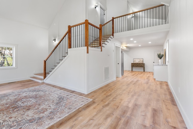 stairway featuring hardwood / wood-style flooring and high vaulted ceiling