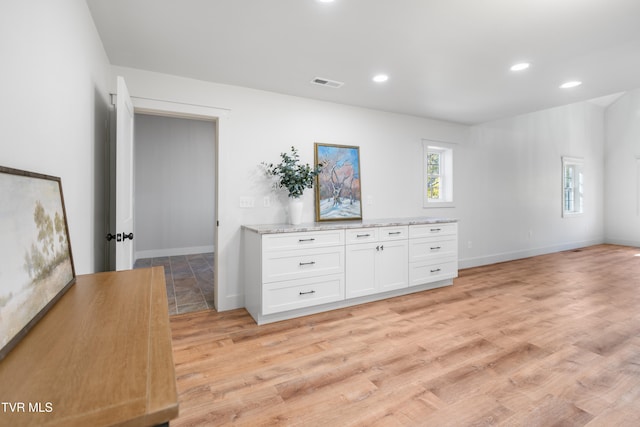 interior space featuring white cabinetry, light stone counters, and light hardwood / wood-style floors