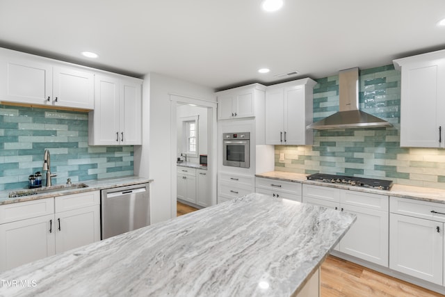 kitchen with wall chimney range hood, white cabinets, tasteful backsplash, and stainless steel appliances