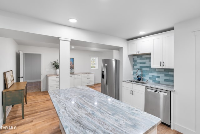 kitchen featuring sink, light stone countertops, white cabinets, appliances with stainless steel finishes, and light hardwood / wood-style floors