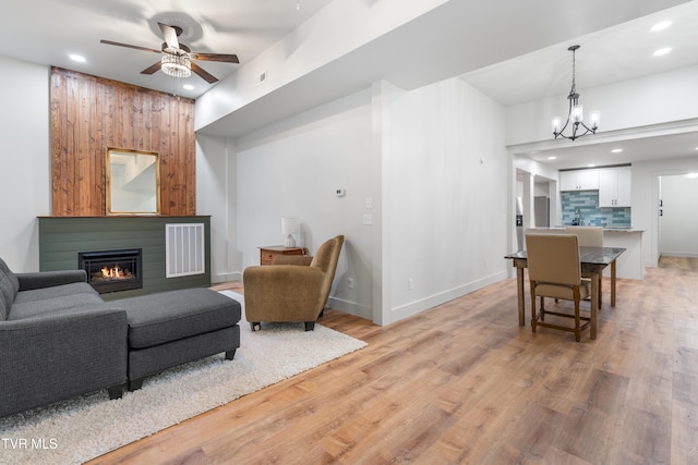 living room with ceiling fan with notable chandelier and light hardwood / wood-style floors