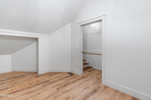 additional living space featuring vaulted ceiling and light wood-type flooring