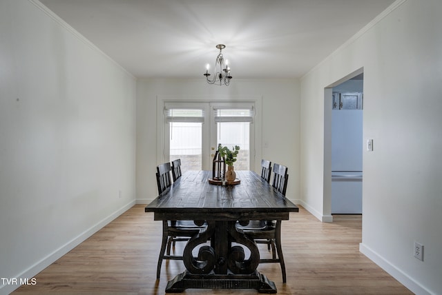 dining space featuring french doors, ornamental molding, light wood-type flooring, and a notable chandelier