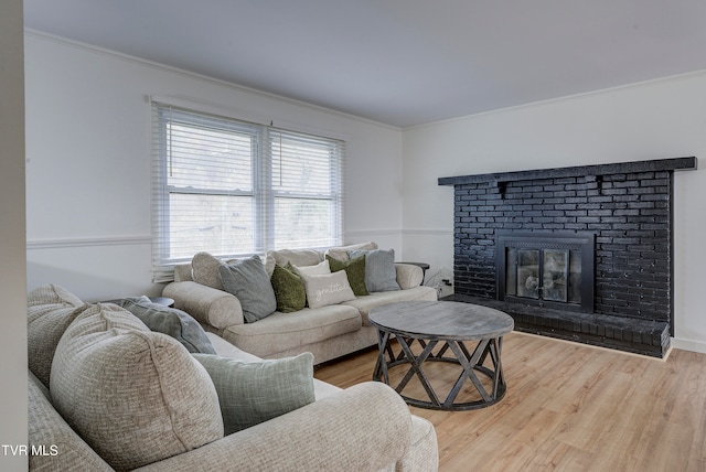 living room featuring a fireplace, crown molding, and wood-type flooring