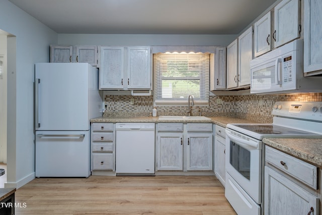 kitchen featuring tasteful backsplash, white appliances, sink, and light hardwood / wood-style flooring