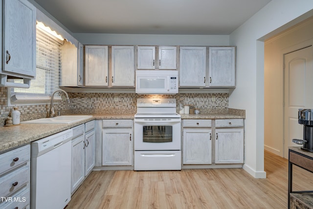 kitchen featuring white appliances, light hardwood / wood-style floors, sink, and backsplash