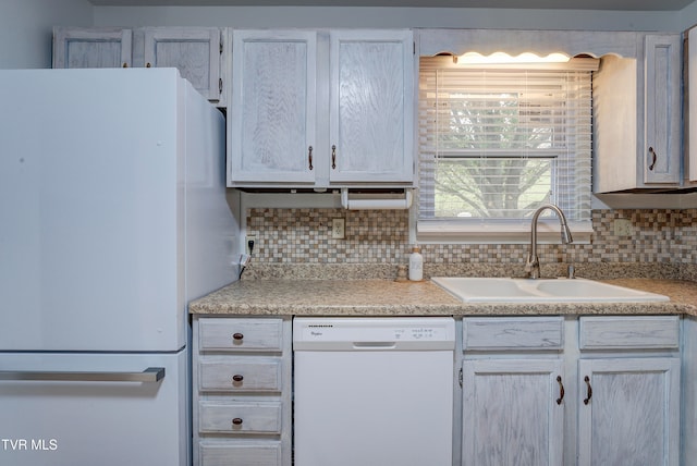 kitchen featuring sink, white appliances, and backsplash