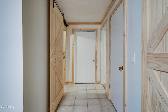 hallway with a barn door and a textured ceiling