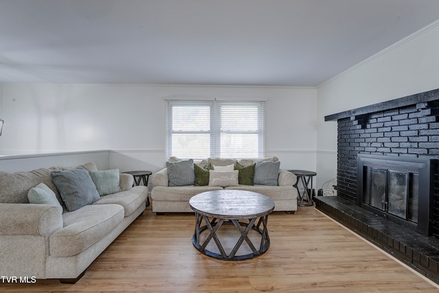 living room with ornamental molding, a brick fireplace, and light hardwood / wood-style floors