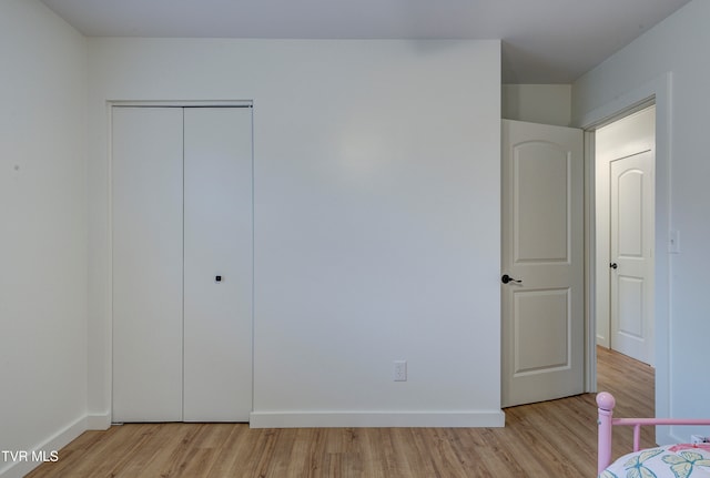 unfurnished bedroom with a closet and light wood-type flooring