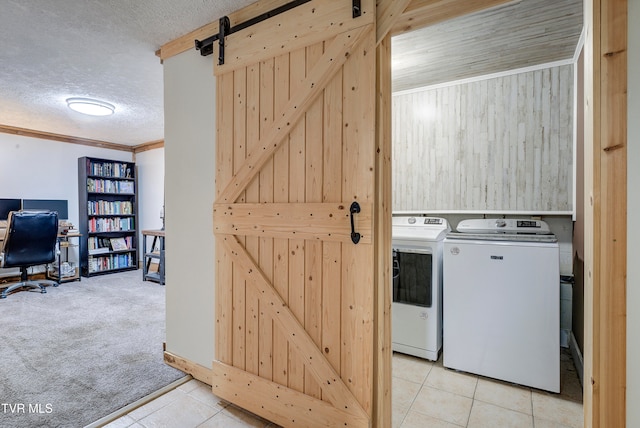 laundry area with washer and dryer, ornamental molding, light colored carpet, a barn door, and a textured ceiling