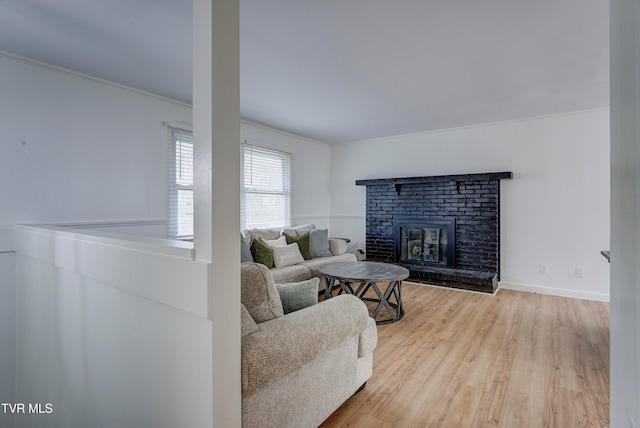 living room with crown molding, a fireplace, and light hardwood / wood-style flooring