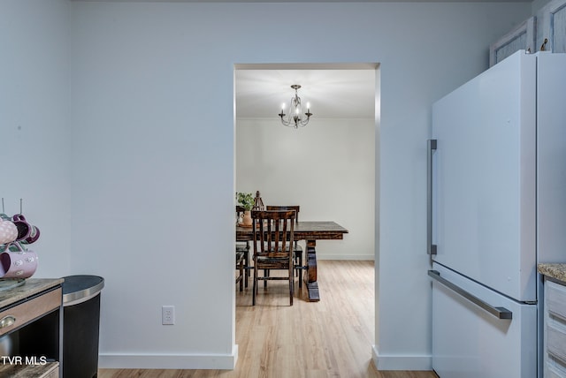 kitchen featuring hanging light fixtures, white fridge, an inviting chandelier, and light hardwood / wood-style floors