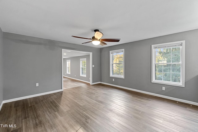 spare room with baseboards, visible vents, wood finished floors, and ceiling fan