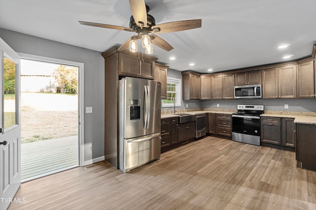 kitchen with dark brown cabinets, light wood-type flooring, and appliances with stainless steel finishes