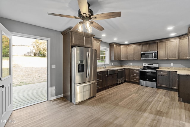 kitchen with recessed lighting, a sink, a ceiling fan, light wood-style flooring, and appliances with stainless steel finishes