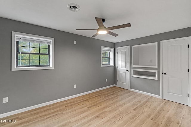 unfurnished bedroom featuring two closets, light wood-type flooring, baseboards, visible vents, and a ceiling fan