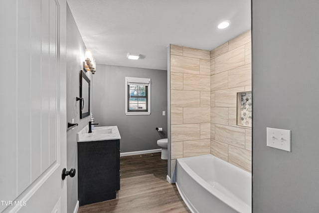 full bathroom with vanity, hardwood / wood-style floors, toilet, and washtub / shower combination