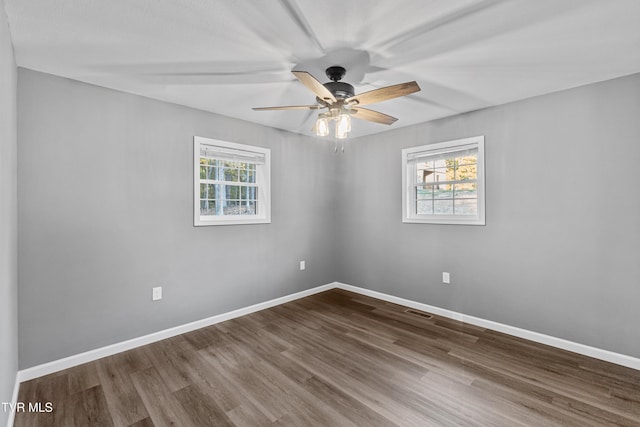 spare room with baseboards, visible vents, wood finished floors, and a ceiling fan