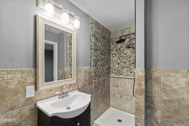 bathroom with vanity, a tile shower, and tile walls