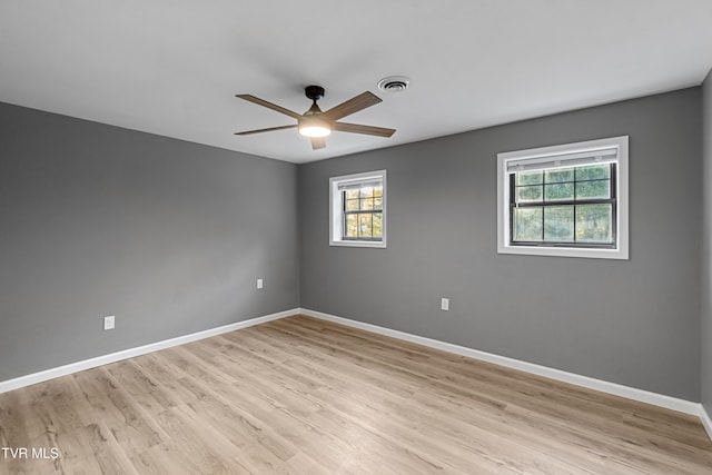 empty room featuring baseboards, light wood-type flooring, visible vents, and a ceiling fan