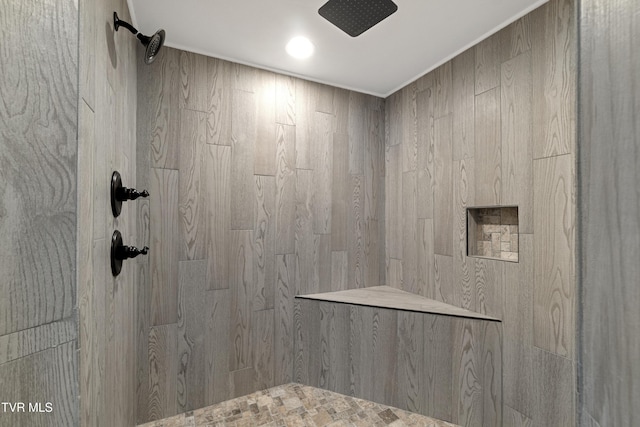 bathroom featuring wooden walls and tiled shower