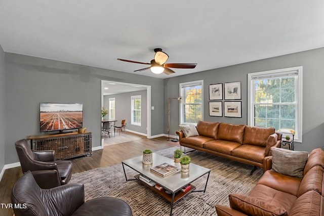 living area with wood finished floors, a ceiling fan, and baseboards
