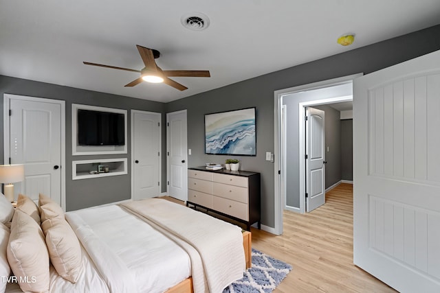 bedroom featuring light wood finished floors, a ceiling fan, visible vents, and baseboards