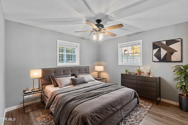 bedroom with a ceiling fan, wood finished floors, and baseboards