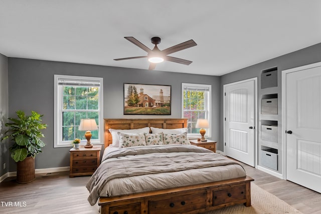 bedroom with hardwood / wood-style floors, ceiling fan, and multiple windows