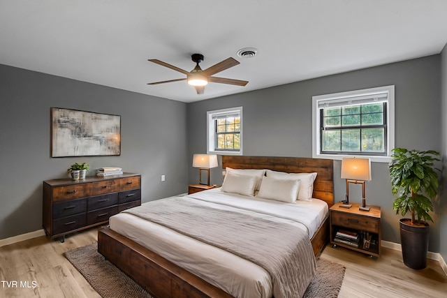 bedroom featuring a ceiling fan, visible vents, baseboards, and light wood-style floors